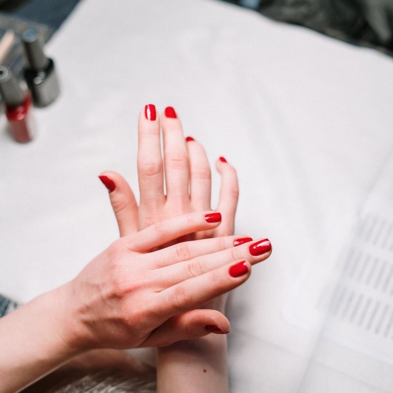 Handen met verzorgde rode nagels